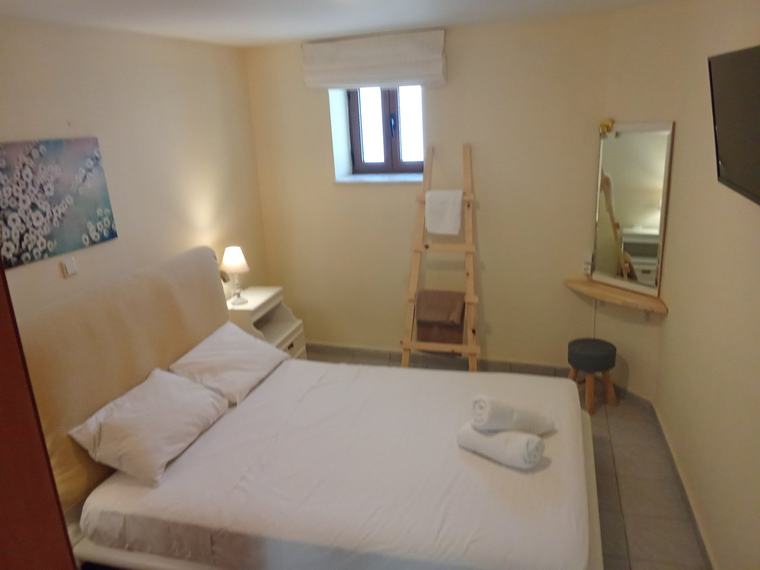 Double bedroom with grey upholstered headboard, pendant reading lights and a wooden towel ladder
